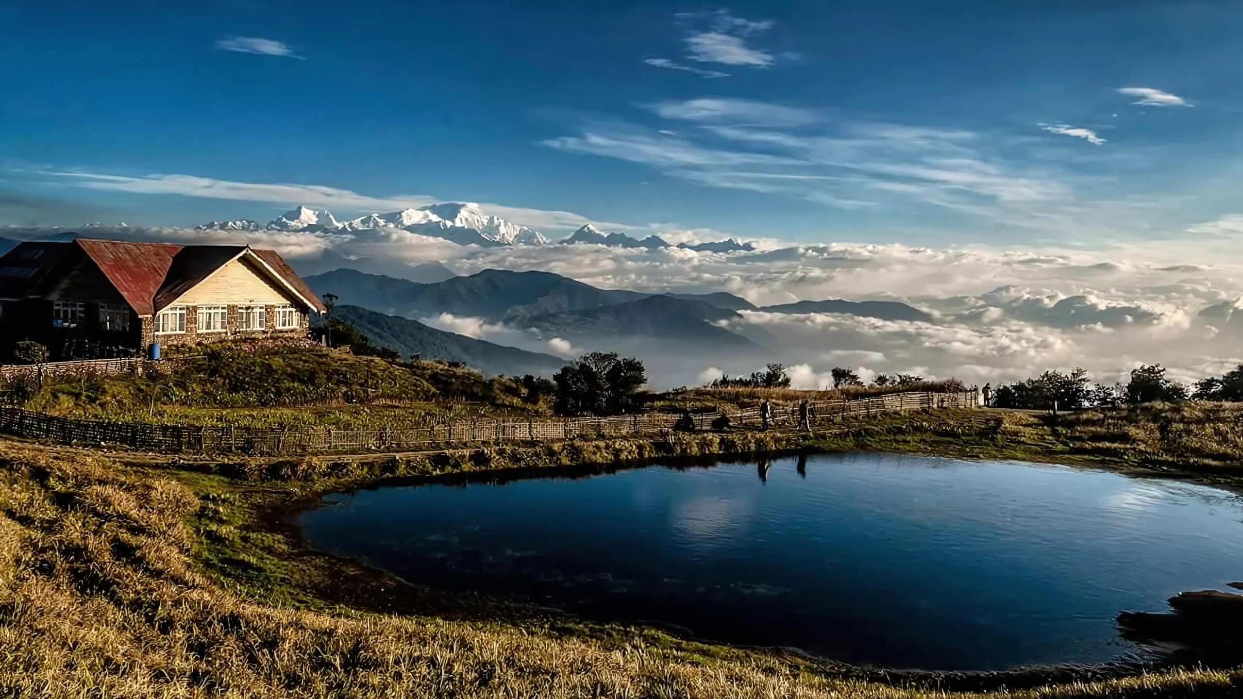 Snow-capped Himalayan peaks above mountain cottages and a tranquil lake
