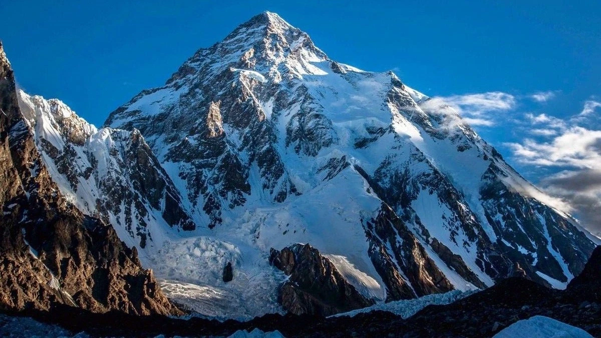 A dramatic snow-covered mountain summit and glacier beneath a clear blue sky
