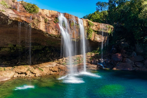 Krang Suri waterfall flowing into a turquoise pool beneath a blue sky in Meghalaya